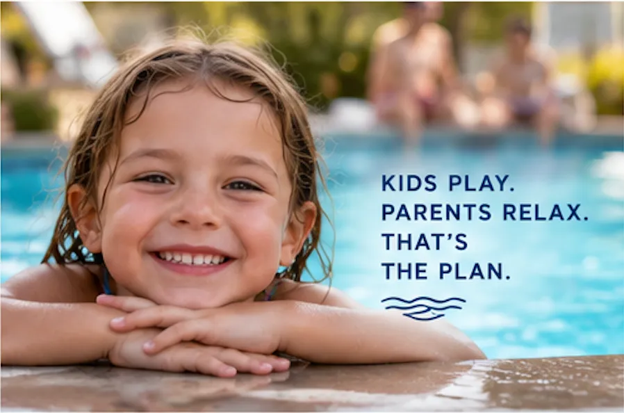 A smiling child rests her arms on the pool edge while adults relax in the background.
